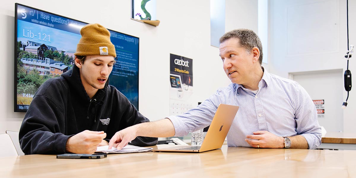 professor Ben Schachter assisting a student in class room at a table