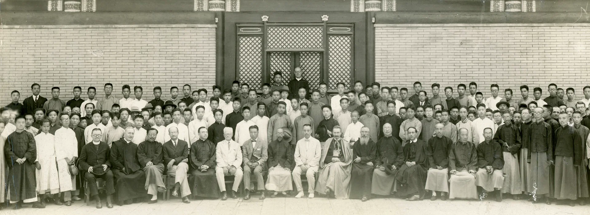 Historical group portrait of a large gathering of men in traditional Chinese attire, showcasing a diverse assembly in a formal setting.