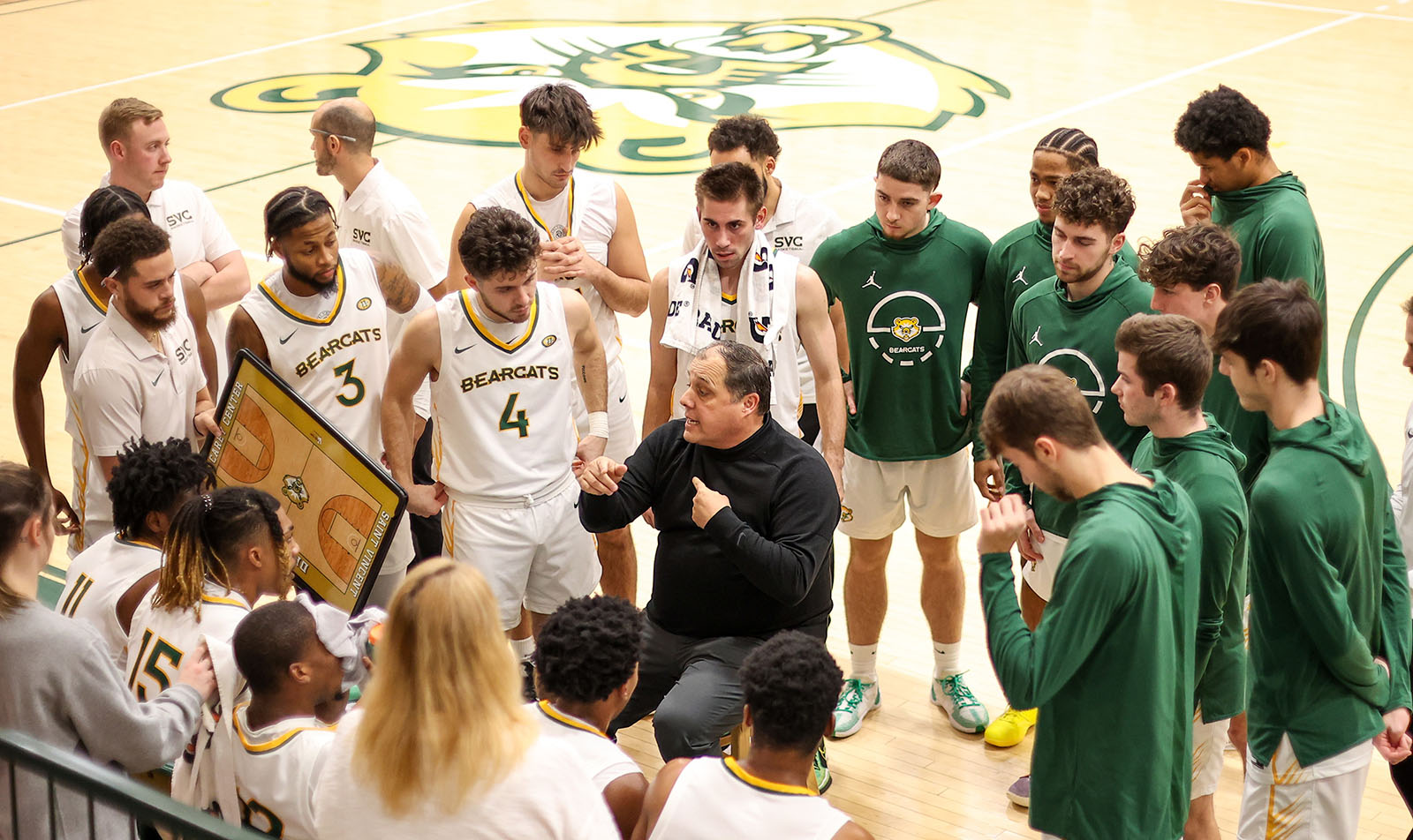 photo of DP Harris in huddle with Saint Vincent basketball team on the sidelines during a game