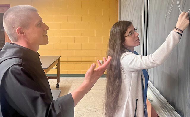 Photo of Fr. Michael Antonacci and Dr. Mary Regina Boland in a classroom at Saint Vincent College writing notes on a blackboard