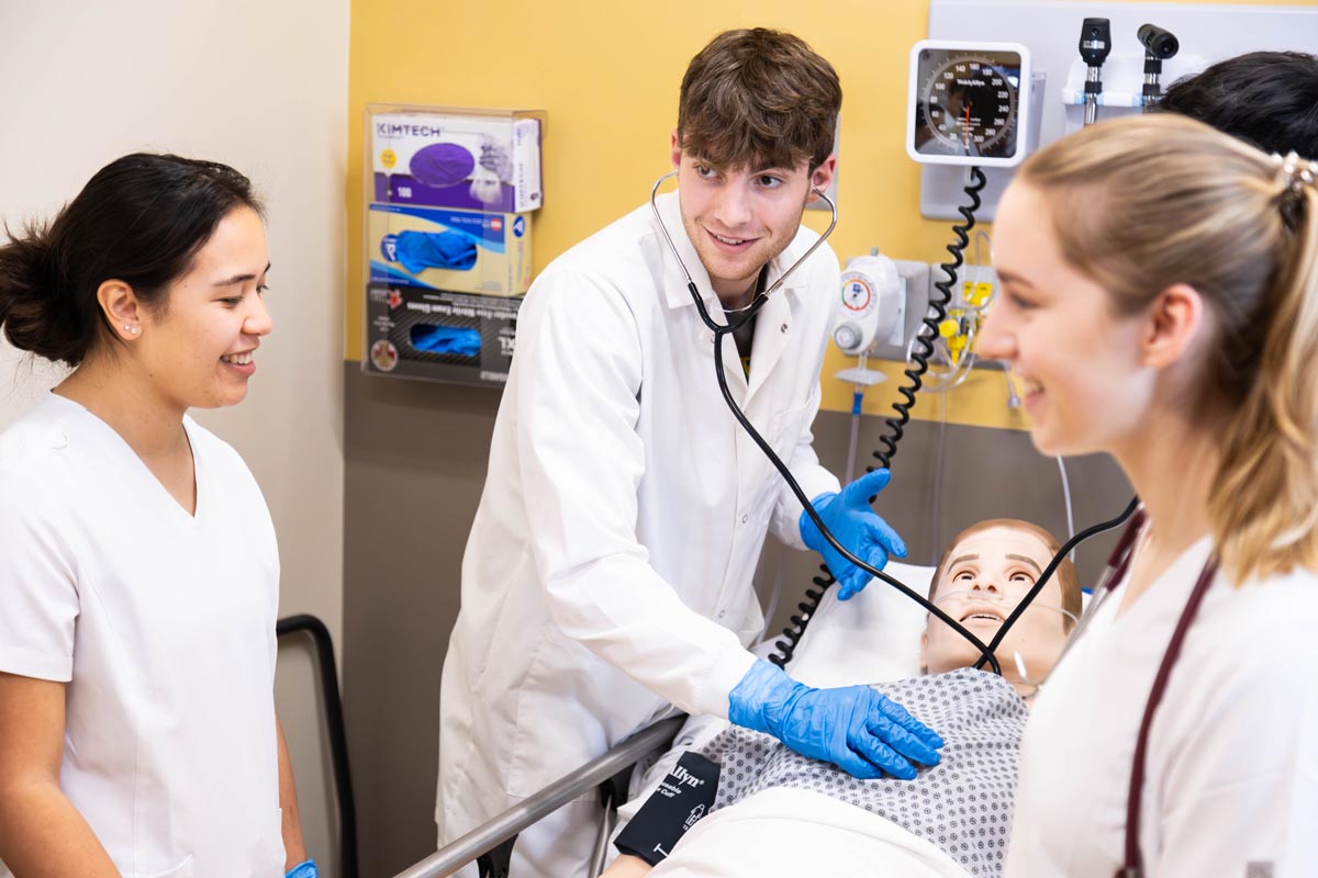 three students at Saint Vincent College test their skills in a simulated hospital setting.