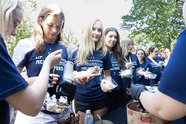 Group of volunteers in blue t-shirts serving ice cream at a community event.