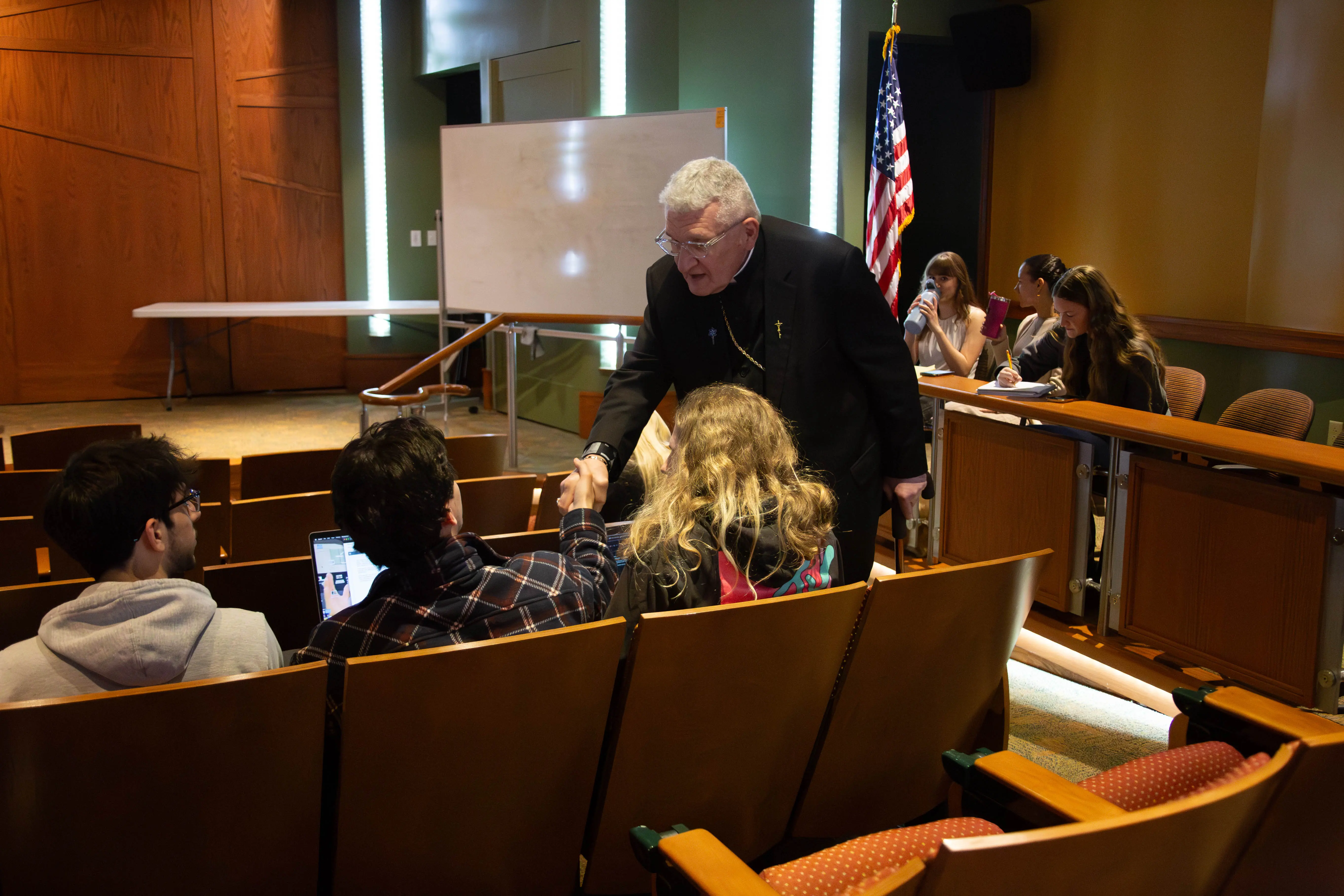 A speaker engages with students in a classroom setting, emphasizing interaction and participation during a discussion.