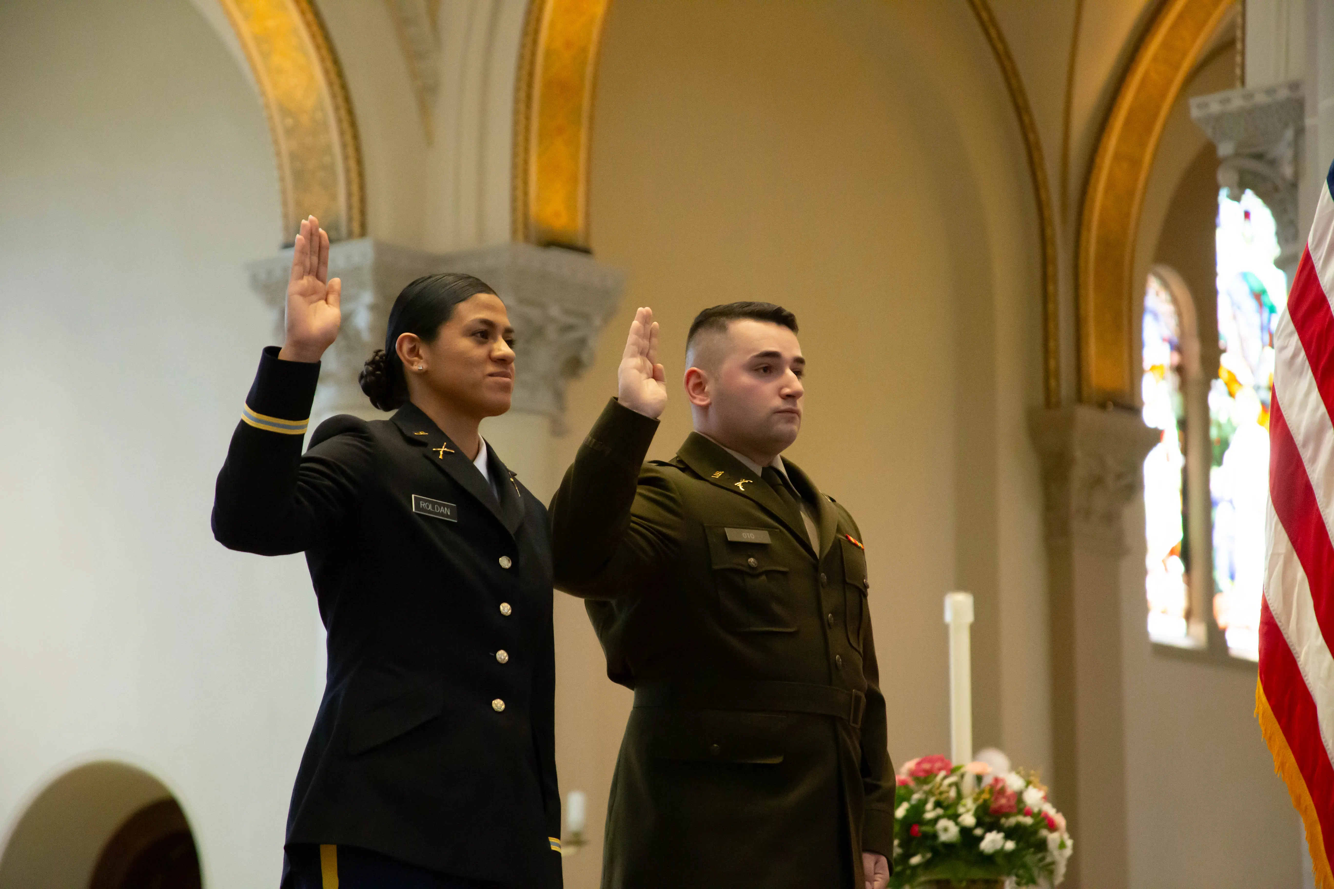 Two military personnel taking an oath during a formal ceremony.