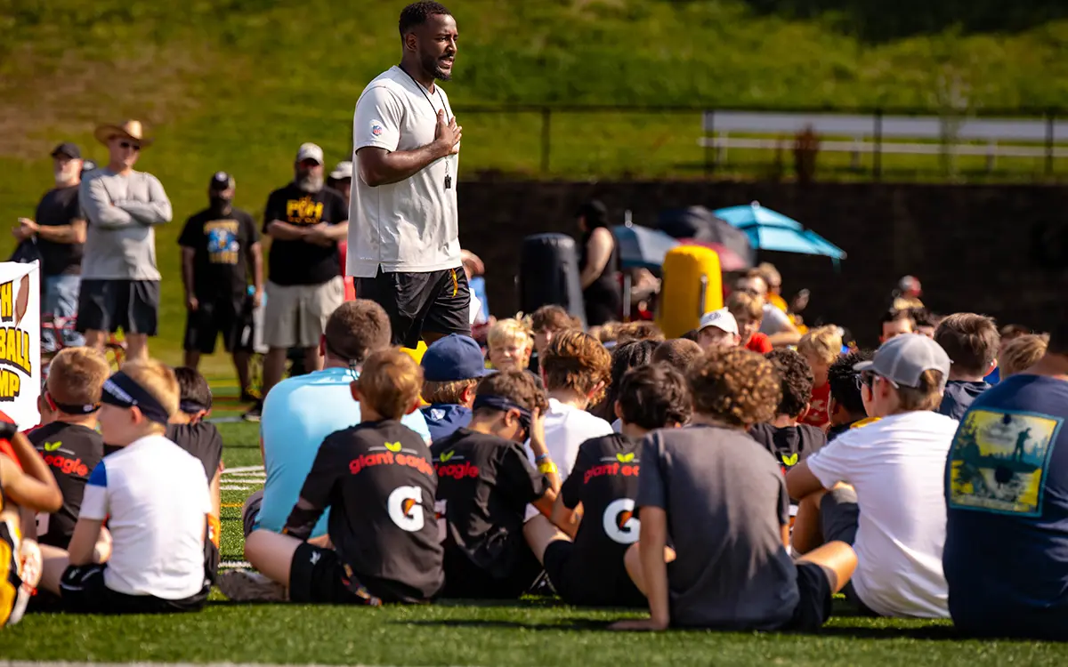 Joe Lofton speaks to a group of young athletes at a sports camp, emphasizing teamwork and motivation.