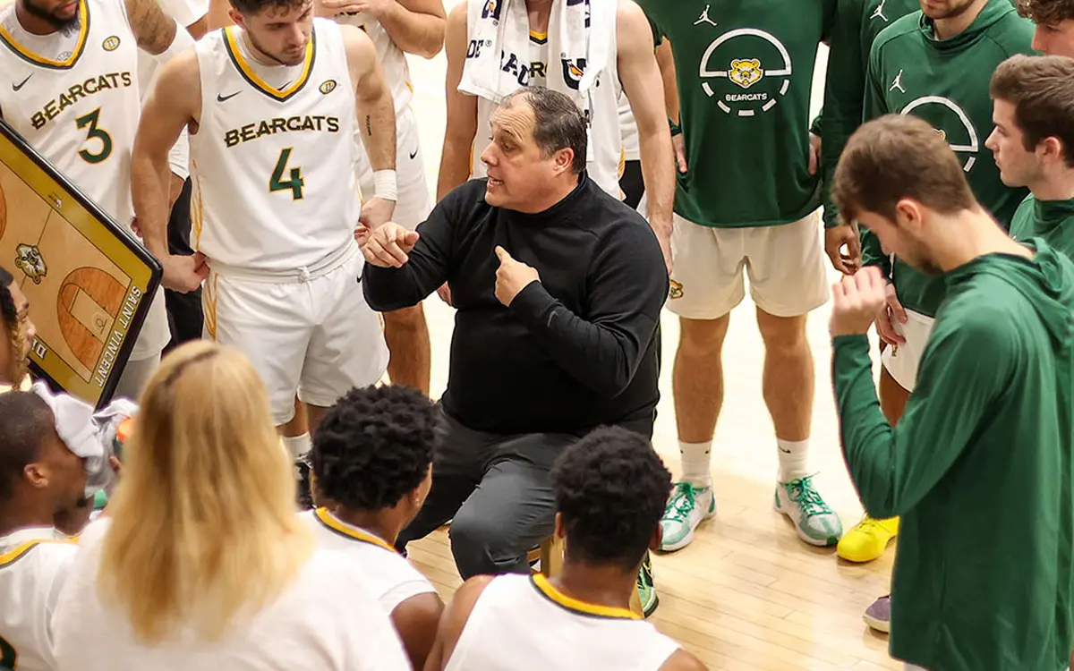 Basketball coach giving instructions to his team during a timeout.