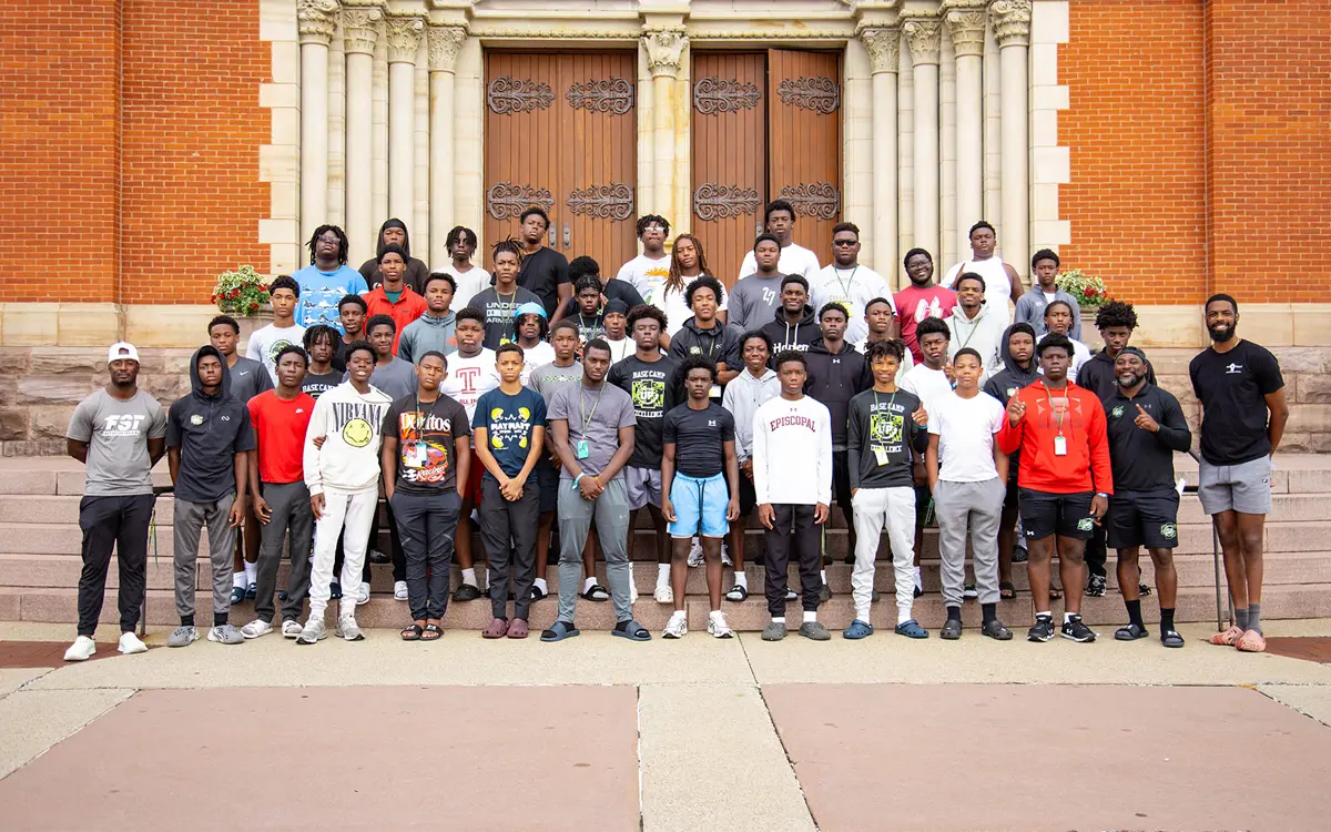 Group photo of a diverse group of young men standing together in front of a historic building.